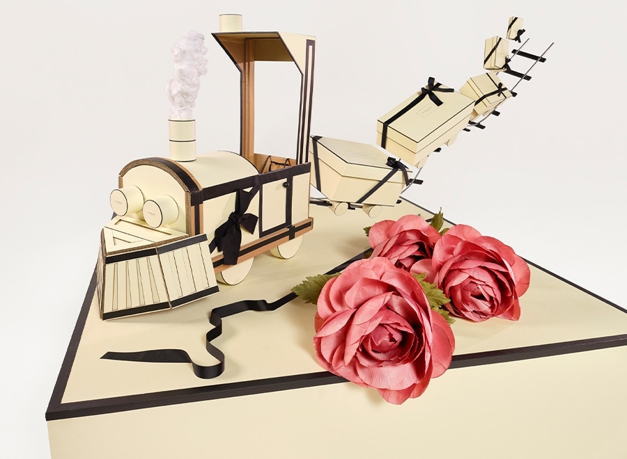 Caixa de presente Jo Malone em formato de trem na cor creme e fita preta e uma flor rosa