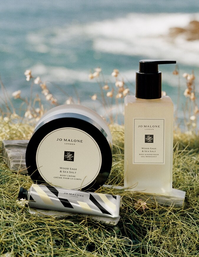 Jo Malone London Wood Sage & Sea Salt body crème, body wash, and silver striped hand cream in seaside grass.